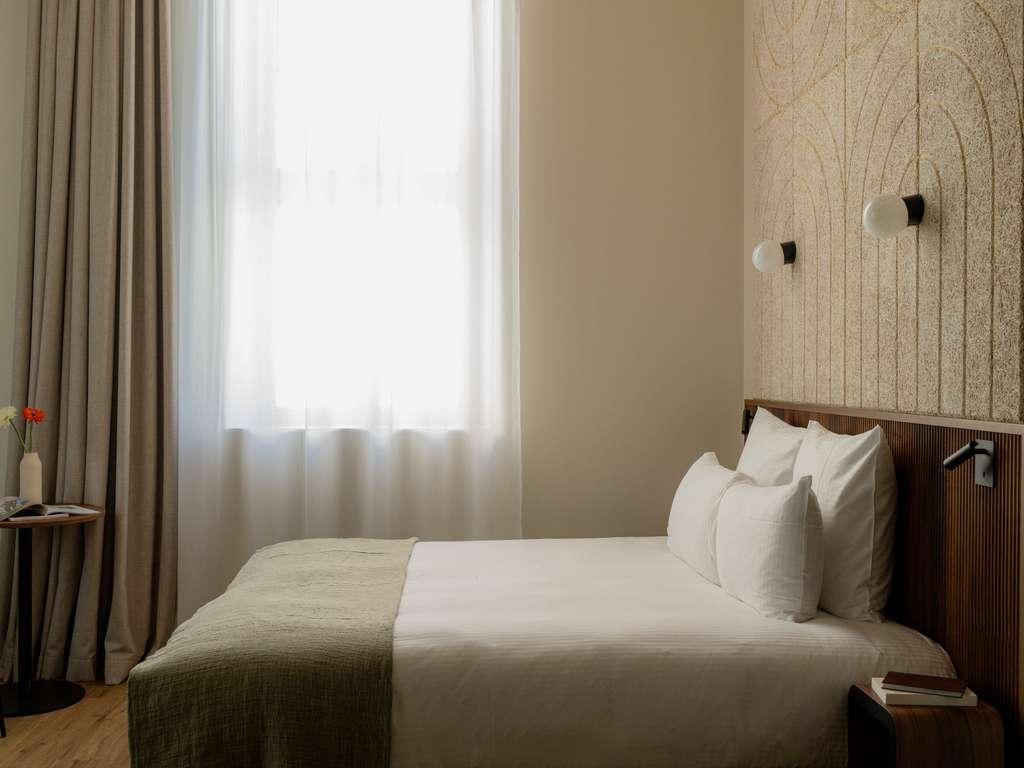 Minimalist French hotel bedroom with natural light, neutral textiles and refined contemporary design